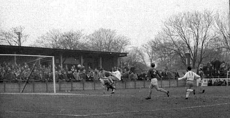 Tommy Jenkins challenges the keeper and the ball appears to be on its way into the net. Gordon Burden is the player running in.
